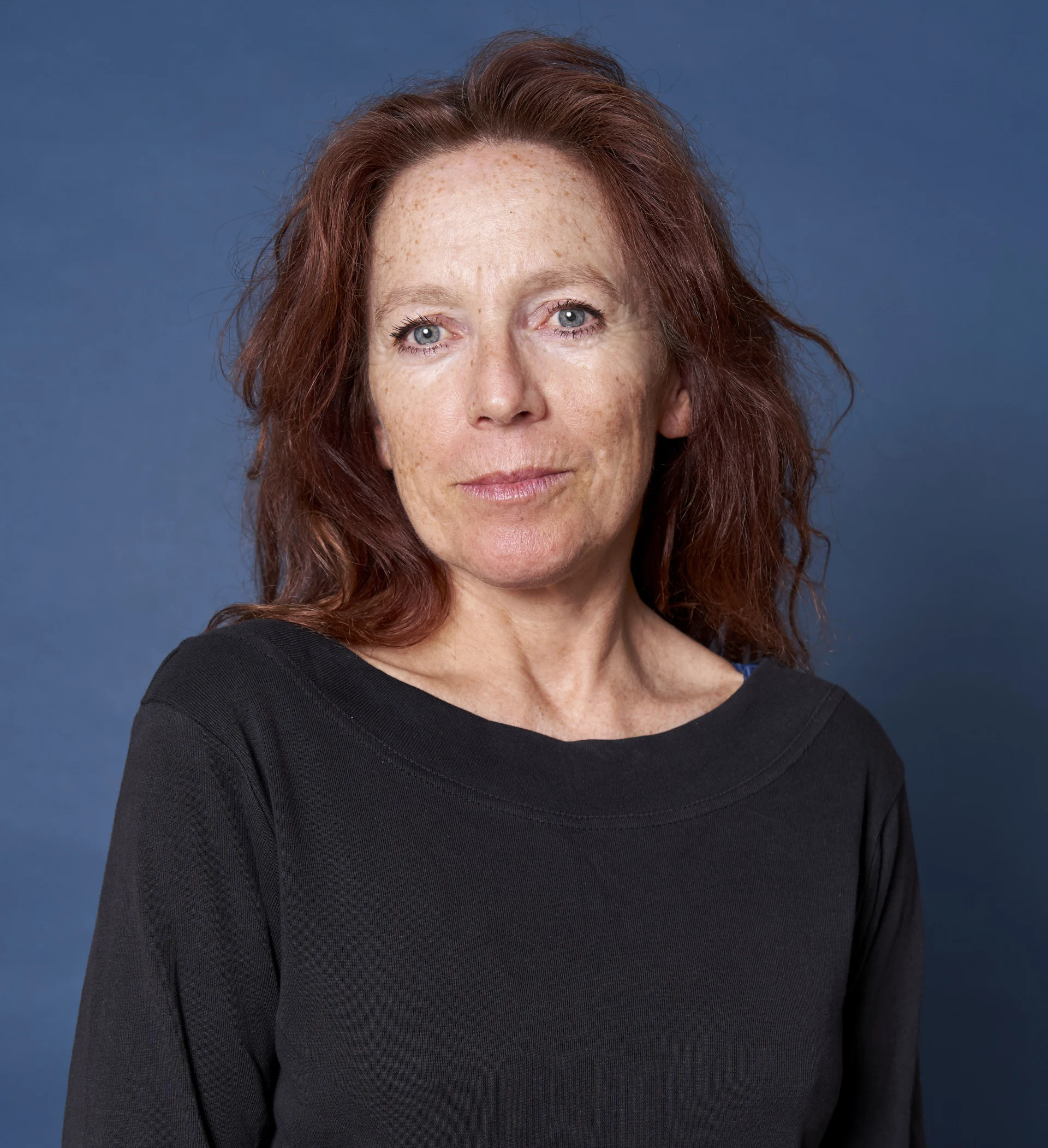 Foto unserer Bereichsleitung. Sie trägt rote, lange Haare und lächelt leicht.