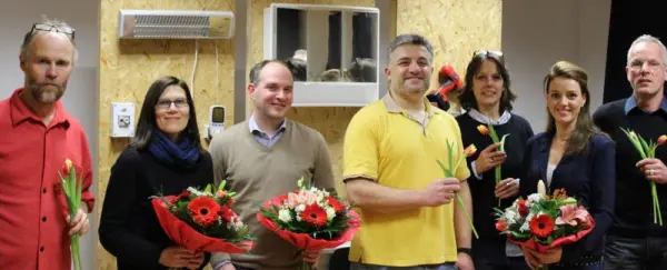 Gruppenfoto von Partner*innen des Wohnführerscheins mit Blumensträußen
